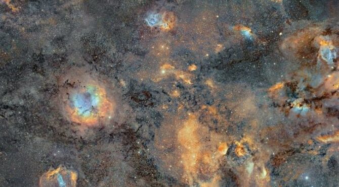 Derin uzayda turuncu, mavi ve mor tonlarında gaz bulutları ile yıldızlarla bezeli sakin bir nebula görüntüsü.